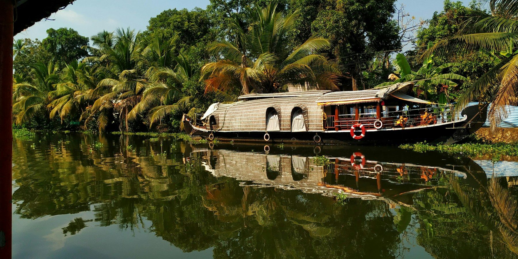 A houseboat reflected in a palm-lined canal
