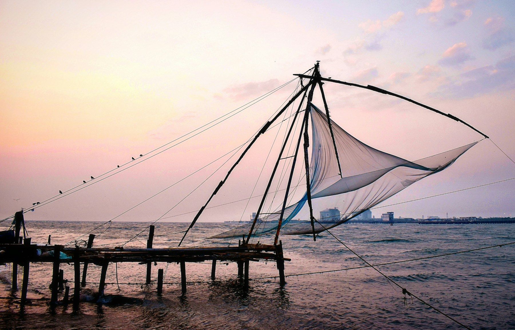 A Chinese fishing net silhouetted against a pink sky